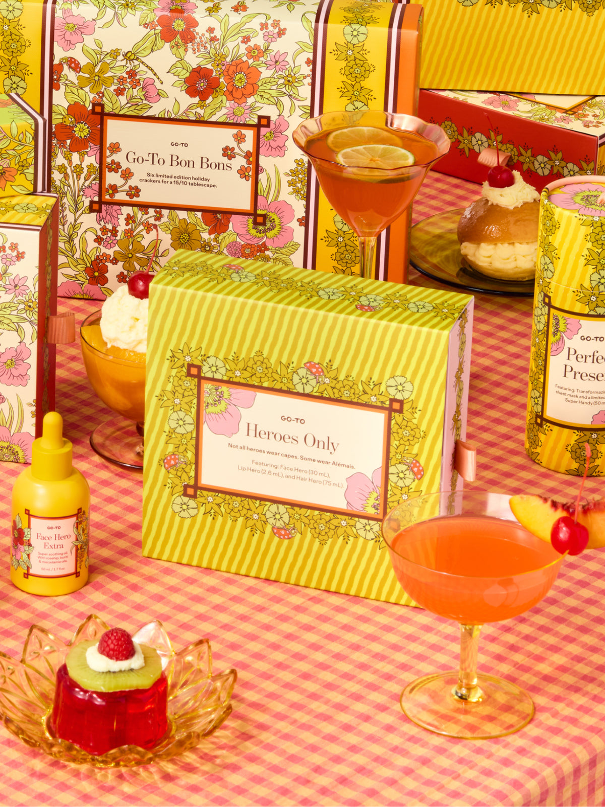 Go-To Skincare Heroes Only gift set in a floral yellow box displayed with skincare bottles cocktails and desserts on a pink gingham tablecloth