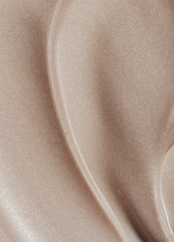 Close-up of a smooth, shimmery beige surface with flowing, wavy lines and a metallic sheen.
