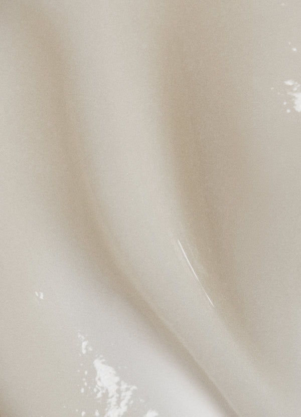 Close-up of a smooth, creamy beige surface with subtle waves and soft highlights, creating an abstract and gentle texture.