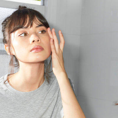 Girl applying skin care in mirror