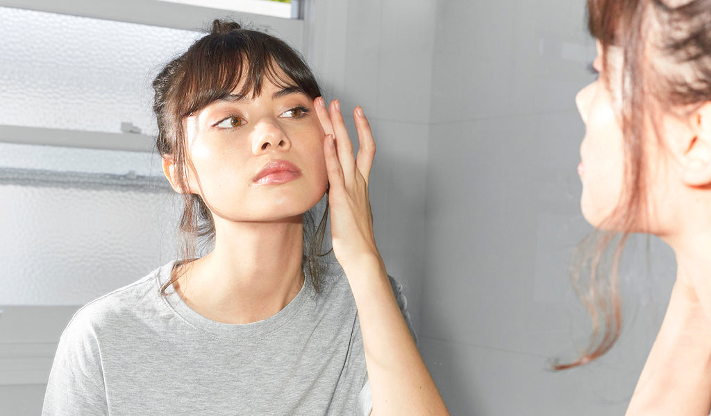 Girl applying skin care in mirror