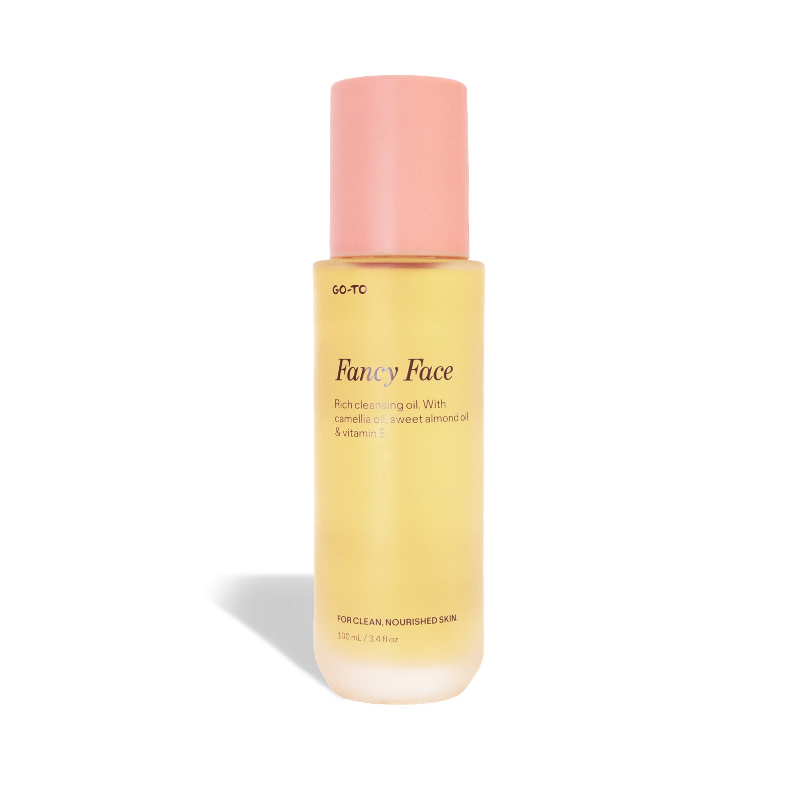 A bottle of Go-To Skincare's Fancy Face, a nourishing oil cleanser with a frosted yellow body and pink cap, features botanical oils like camellia and sweet almond plus vitamin E for clean, nourished skin.