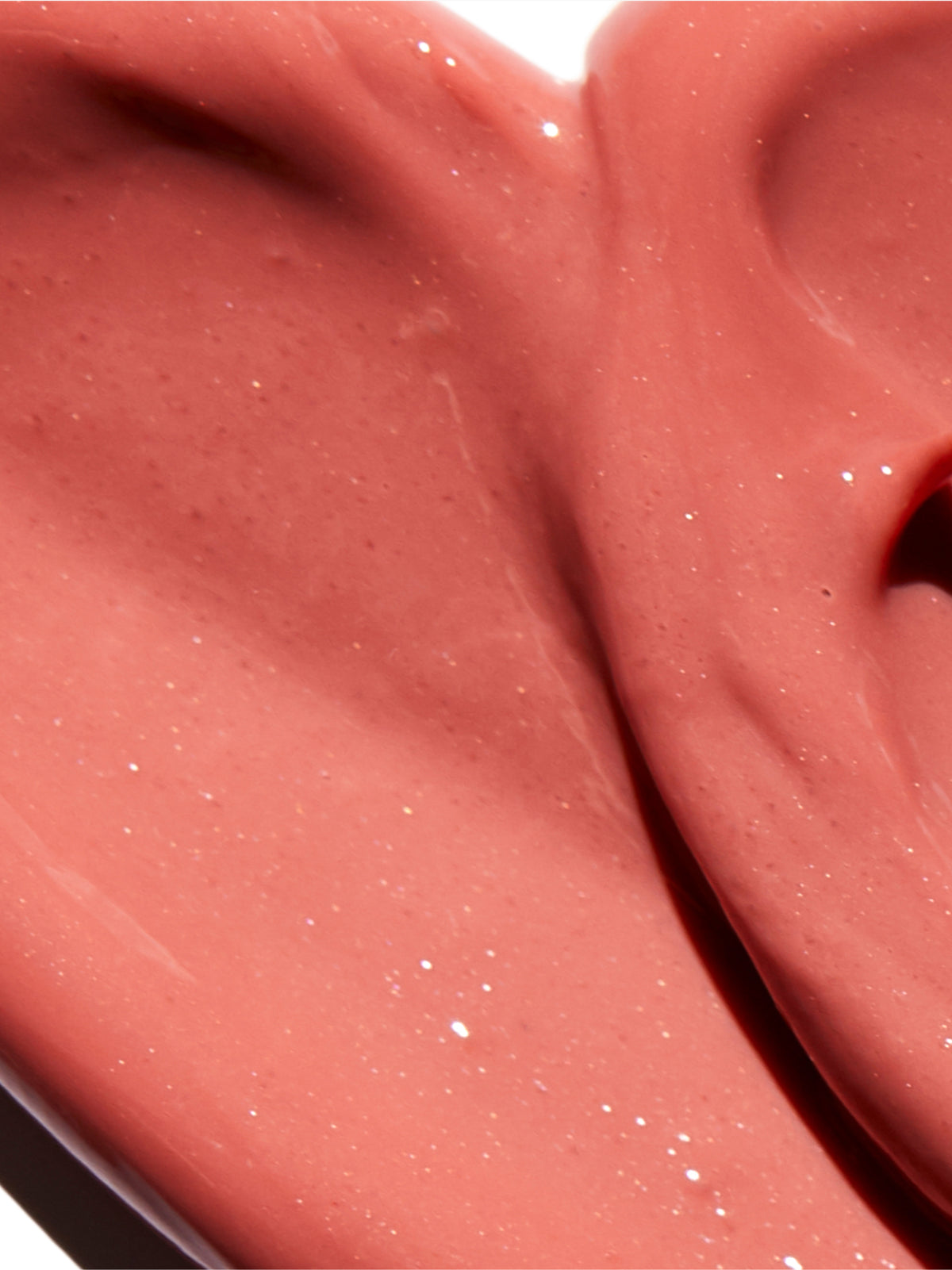 Close-up of Go-To Skincare Glazed tinted SPF lip oil swatch in a pink coral shade with a glossy finish and fine reflective shimmer