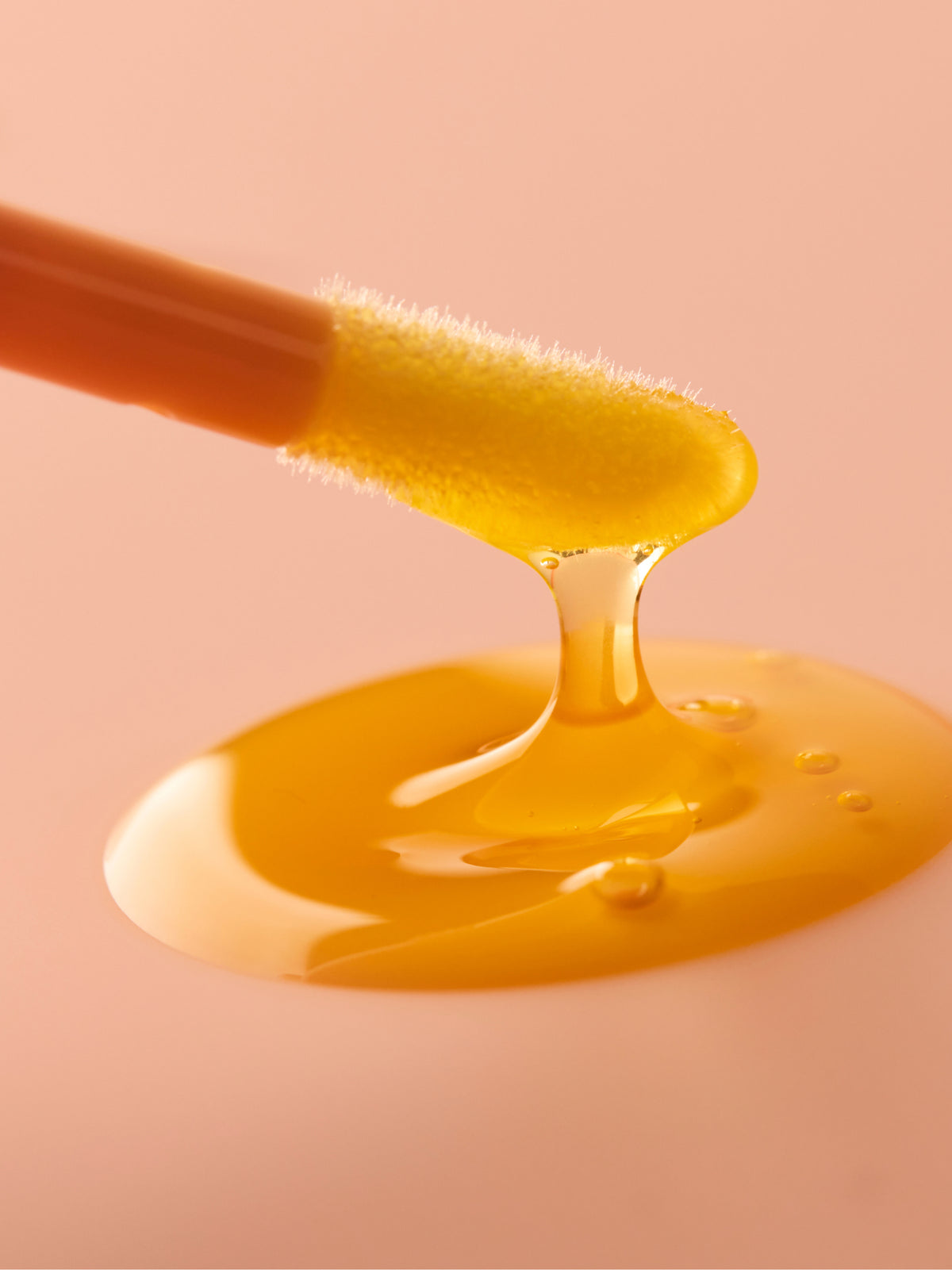 Close up of golden skincare oil dripping from a soft brush onto a glossy pool for Go To Skincare Heroes Only gift set