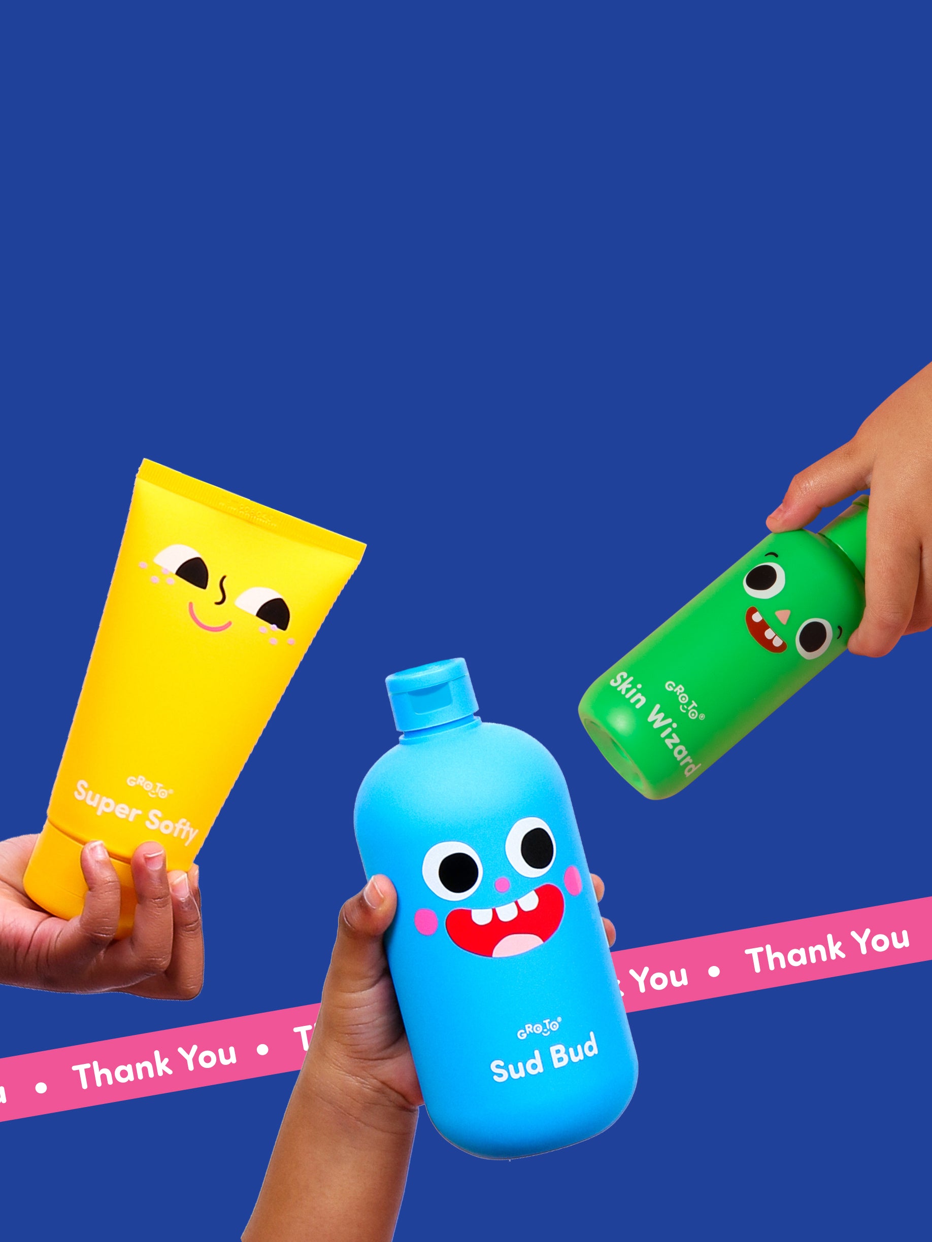 Three hands hold colorful bottles with smiling faces and playful designs on a blue background. The products are labeled Super Softy, Sud Bud, and Skin Wizard. Pink Thank You text appears at the bottom.